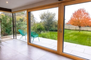 Minimalist sliding door system with timber-aluminium frames, opening onto landscaped garden in Oxfordshire – an example of glazing that may require planning approval.