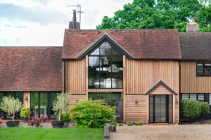 Striking glazed gable with heritage-style framing on a timber-clad barn conversion in the UK countryside — a modern glazing installation that balances contemporary design with planning-sensitive aesthetics.